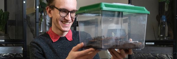 student holding up a plastic case containing bugs
