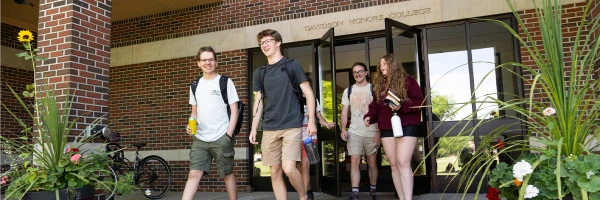 University of Montana students exiting the main entrance of the Davidson Honors College building on the University of Montana campus in Missoula, MT on a sunny day.