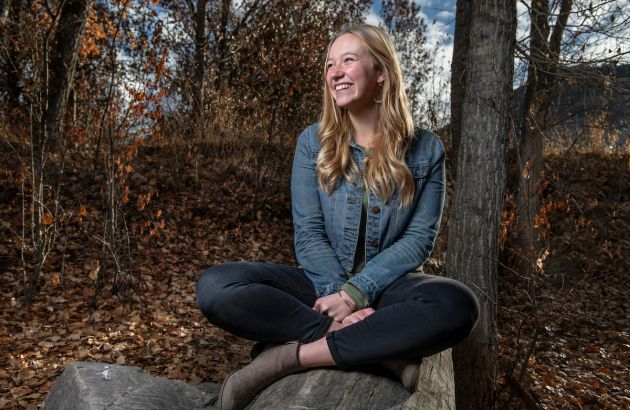 UM student Haley VonGoedert sits on a rock, looking toward her right, smiling