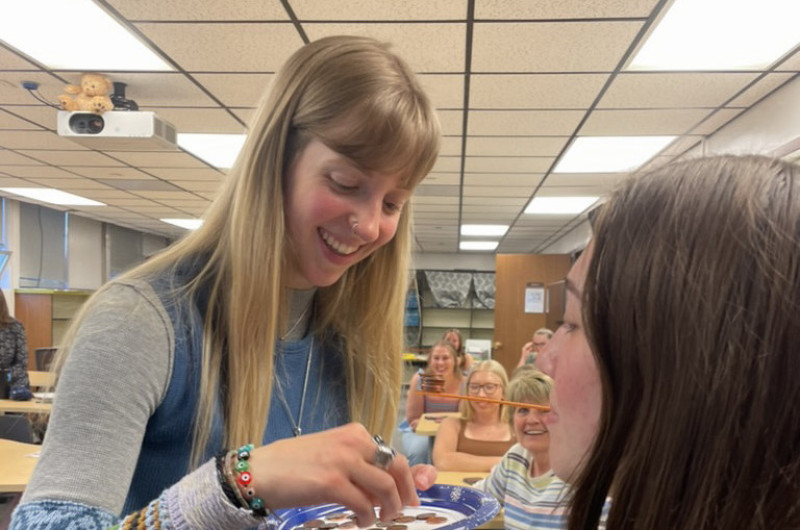 a student on the left practices working with a student on the right who is utilizing a straw with their mouth