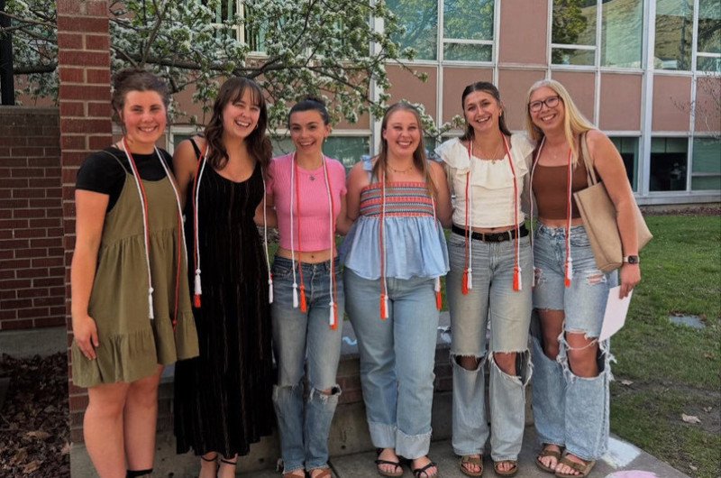 five students in front of Curry Health wearing graduation cords
