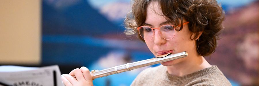 headshot of a student playing a flute and looking at sheet music