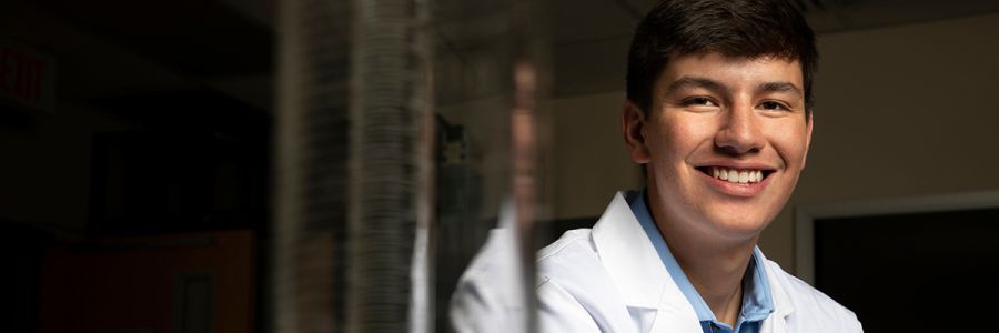 headshot of a student in lab coat smiling at the camera