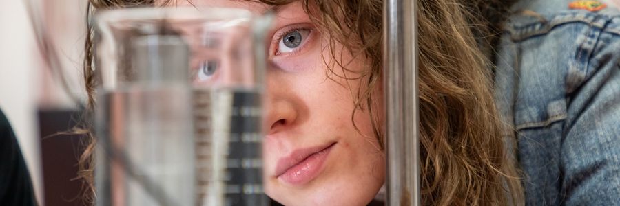 close up view of someone's eye looking through a filled beaker