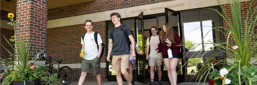 91Ƶ students exiting the main entrance of the Davidson Honors College building on the 91Ƶ campus in Missoula, MT on a sunny day.
