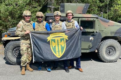 UM law student Paul Hutton holds a flat and poses next to a Humvee, along with other JAG interns.