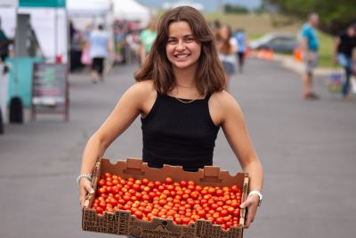 A girl holding a basket of tomatoes