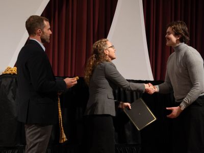 Graduating senior Maxwell shakes hands with Director Gillian Glaes as he receives his Certificate and cords