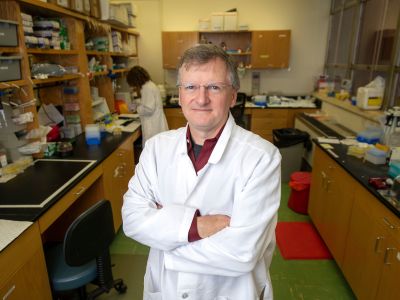 Jay Evans stands in a white lab coat in a lab 