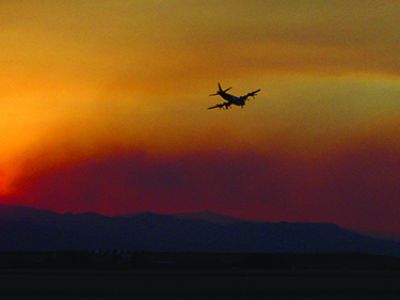 Photo of plane flying over forest fire.