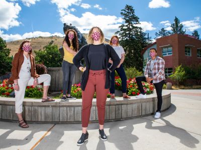 Five people stand in front of the Grizzly Bear statue in masks and the closest person has her hands on her hips 