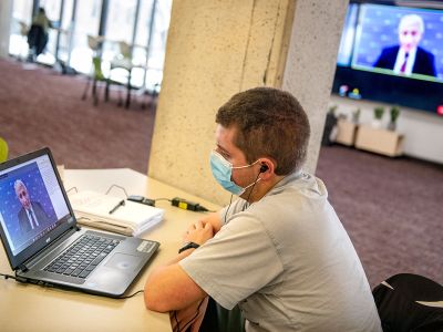 Student Nathaniel Miller watches Dr. Anthony Fauci speak to a UM audience.