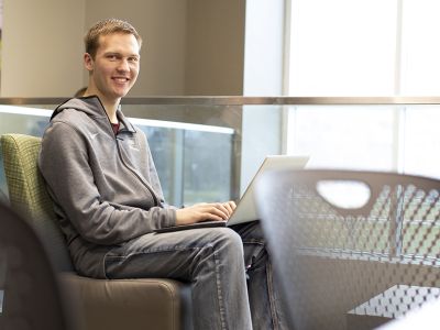 A UM student sits in front of a laptop computer on campus.  