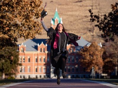 A UM student celebrates graduation before Main Hall.