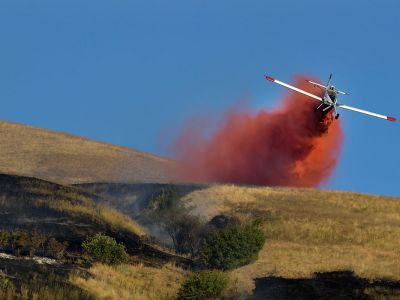 A plane dumps retardant on a fire burning on Mount Sentinel near the UM campus.