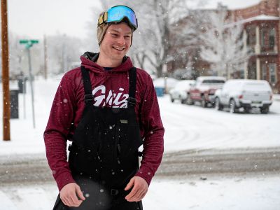A UM student wearing ski goggles stands in the snow.