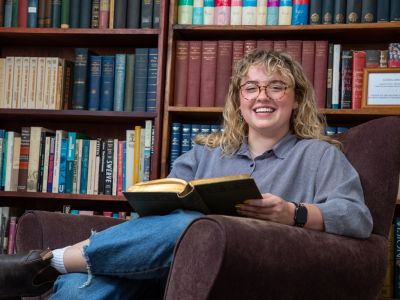 A picture of Maddie Hagan surrounded by books. 