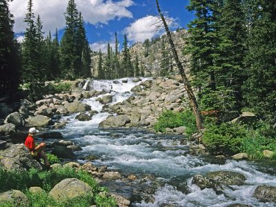 A student sits near a waterfall in the Beartooth Wilderness.