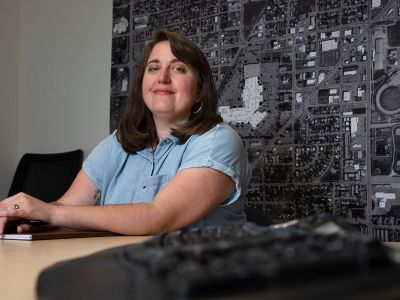 A picture of UM student Ashley Britter Wells in her Missoula office with a city map behind her.
