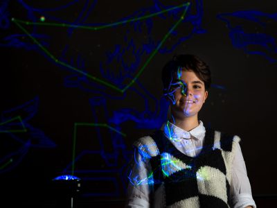 A picture of Ailey Robinson illuminated by projected light in the planetarium of UM's Payne Family Native American Center.