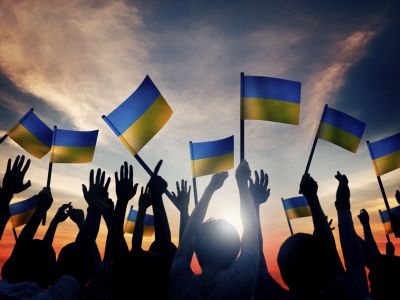 A picture of people holding Ukrainian flags at sunset