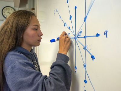 A student writes on a whiteboard.