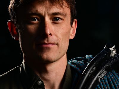 A close-up of Justin Willis with a ropes and ice axes over his shoulder.