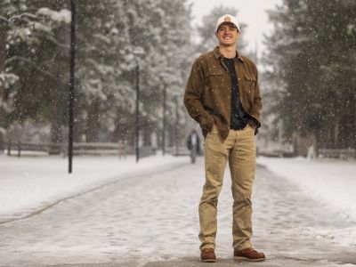 91��Ԫ student James Straw stands for a photo in the falling snow on Memorial Row on campus.