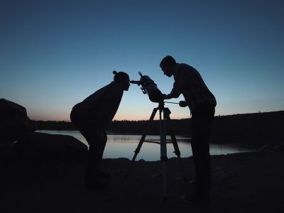 Two people use a telescope at twilight.