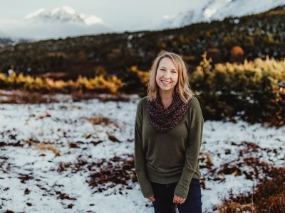 A picture of Heather Johnson standing in a snowy landscape with mountains behind her.