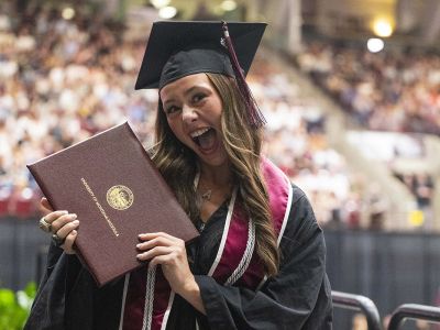 A UM students happily holds her diploma. 