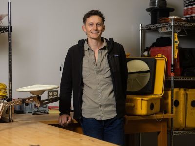 A picture of Matthew Swarr with some science equipment behind him.