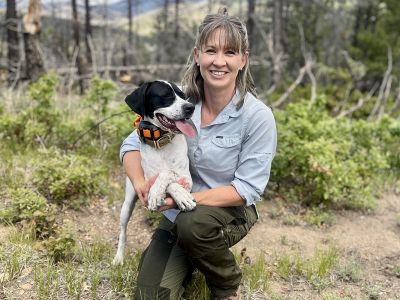 A picture of Nicole Tatman in a forest with a dog.