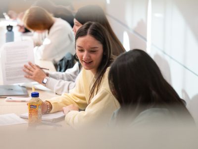 Students at the University of Montana engage in conversation at a table in a classroom.