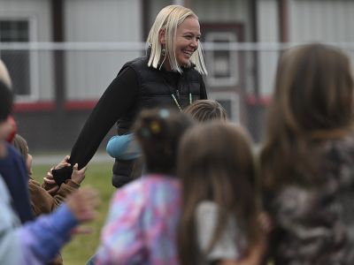 A picture of Kendal Baldwin surrounded by children on the playground.