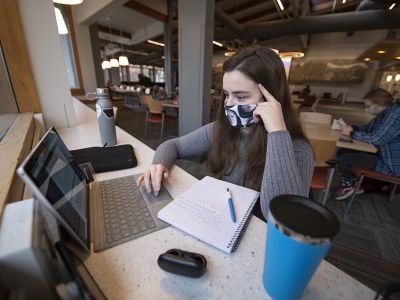 A UM student sits in front of a laptop computer on campus.  