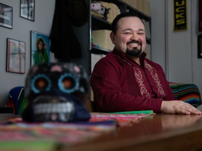 A man sits at a desk and smiles 