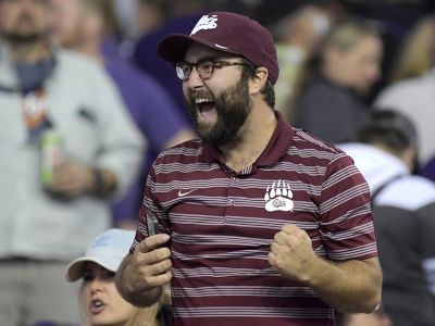 A man wearing a Griz hat cheering in a crowd at a football game