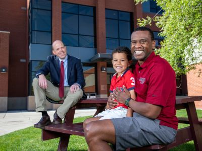 A law professor sits on a picnic table with a law student and his son 