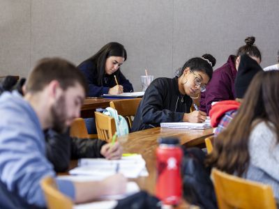 A group of students writes in a notebooks in  classroom. 