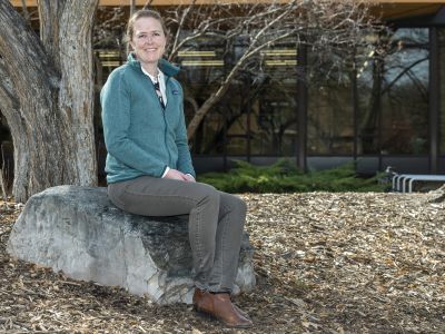 Hilary Martens, in a blue sweatshirt, sits on a rock 