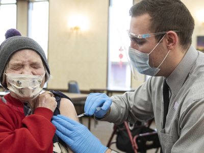 A UM pharmacy student gives the COVID-19 vaccine to an elderly woman. 