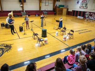 UM music alumni play instruments in a school gymnasium 
