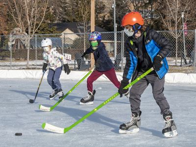 Three children skate on the ice rink on the UM Oval. 