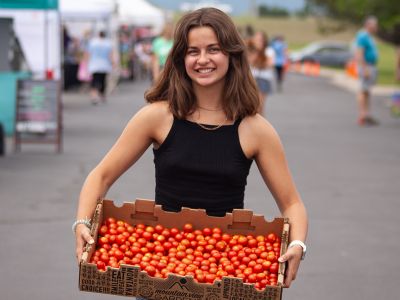 A girl holding a basket of tomatoes