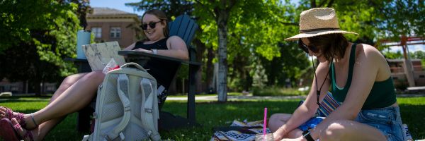 two students studying in the grass around the UM Oval