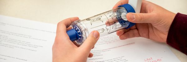 close up of student working with lab equipment on a table above notes