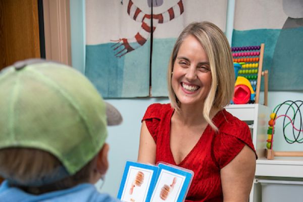 dr severson holds up two cards and smiles while a child looks on