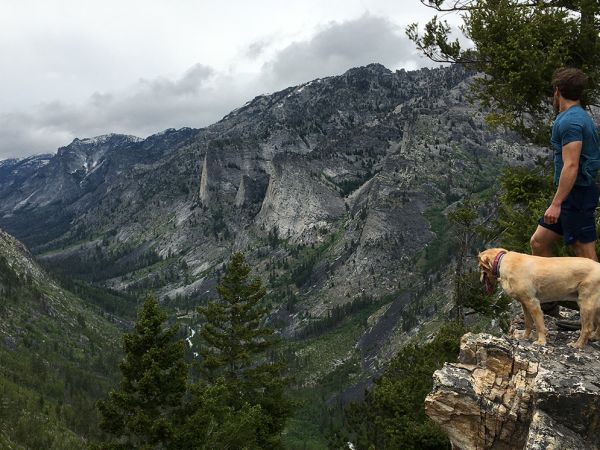 UM student Nate LaCorte and his dog stand on a rock outcrop looking up a mountain canyon in Montana.