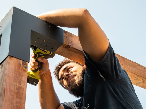 A UM student operates a drill while assembling playground equipment at a volunteer event.